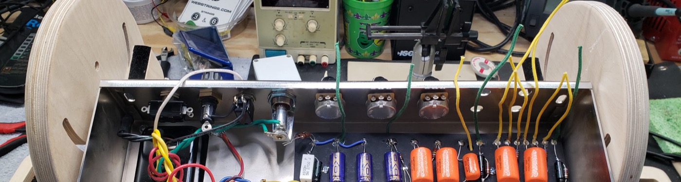 Amp chassis wiring in progress inside a birch cabinet