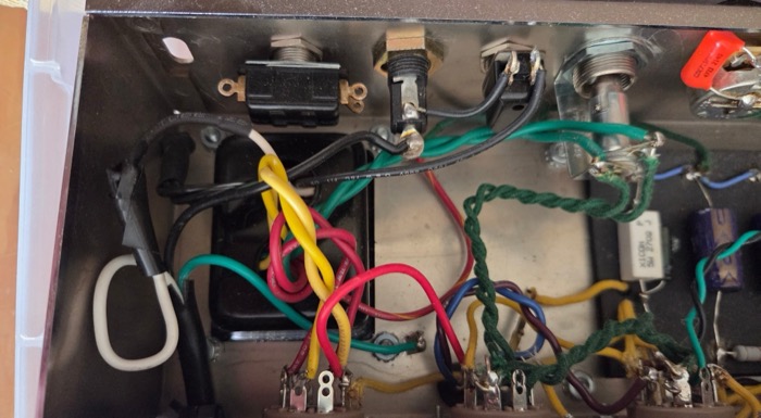 Hand-wired amp chassis with tube sockets and color-coded leads
