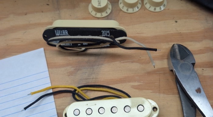 Lollar single-coil pickups and control knobs laid out on the bench